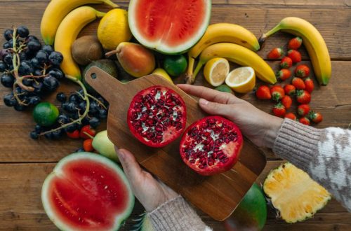 Vibrant fruits including pomegranates, bananas, and watermelon on a rustic wooden table.