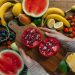 Vibrant fruits including pomegranates, bananas, and watermelon on a rustic wooden table.