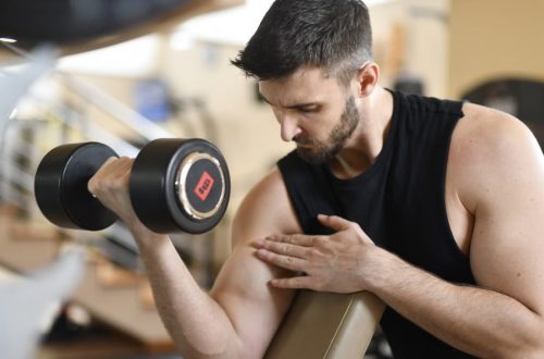 Focused man lifting dumbbell, showcasing strength and fitness indoors.