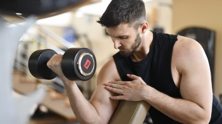 Focused man lifting dumbbell, showcasing strength and fitness indoors.