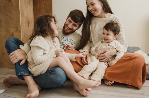 Smiling family of four sitting on the living room floor, enjoying quality time together.